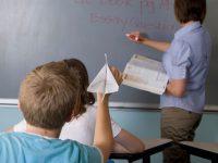 image: Teacher at Chalkboard with student about to throw a paper airplane